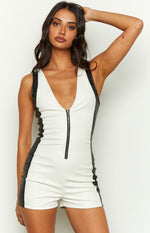 Close-up of the white faux leather playsuit with deep V-neckline, full front zipper, and black side panels