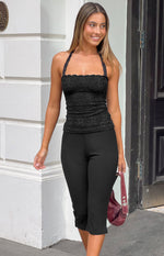 Front view of a black lace halter neck top with a scalloped neckline and fitted silhouette