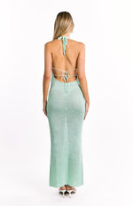 Rear view of a green knit maxi dress featuring a tied halter neck and an open back with thin horizontal ties