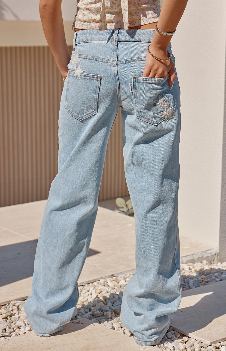 Back view of light wash baggy jeans showing embroidered star details on the back pockets and hip