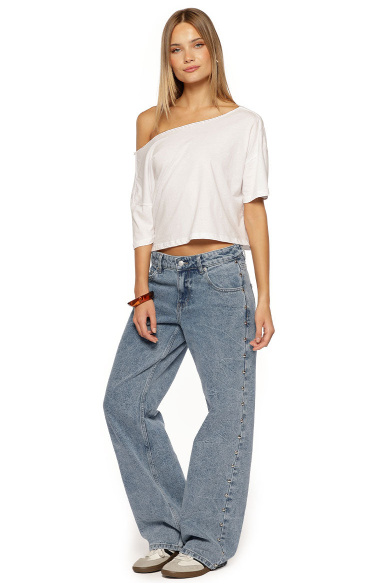 Side view of mid wash denim low waist baggy leg jeans with studs running down the outer seam