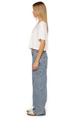Side view of mid wash denim baggy leg jeans with studs down the outer seam