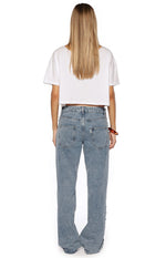 Rear view of mid wash denim low waist baggy leg jeans with back pockets and studded detail along the side seams