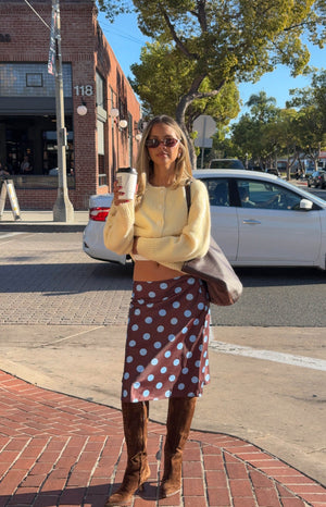 Full length view of a brown midi skirt with light blue polka dots, showing its flowy drape and A-line cut