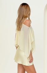 Side view of a yellow sheer chiffon cape with cold-shoulder cutouts and a layered, flowy design