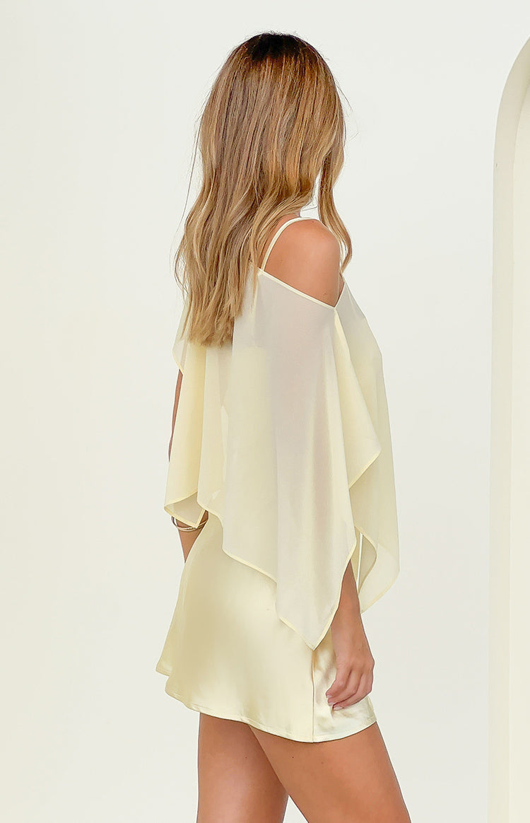 Side view of a yellow sheer chiffon cape with cold-shoulder cutouts and a layered, flowy design