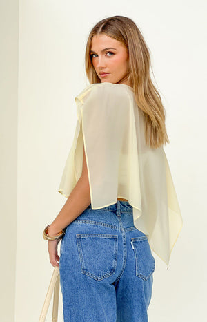 Rear view of a yellow sheer chiffon cape with open arm slits and a flowy, cropped silhouette