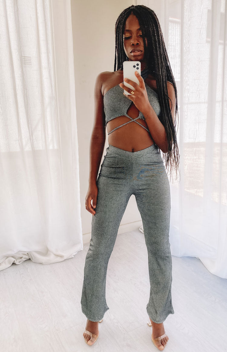 Ribbed dark grey two-piece set with a halter crop top, midriff criss-cross straps, and V-waist flared pants