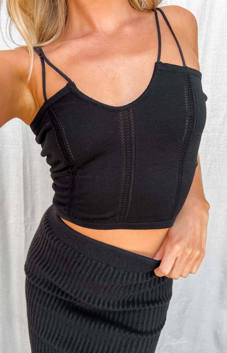 Close-up of the black knit crop top with vertical open-knit panels, ribbed texture, and thin double spaghetti straps