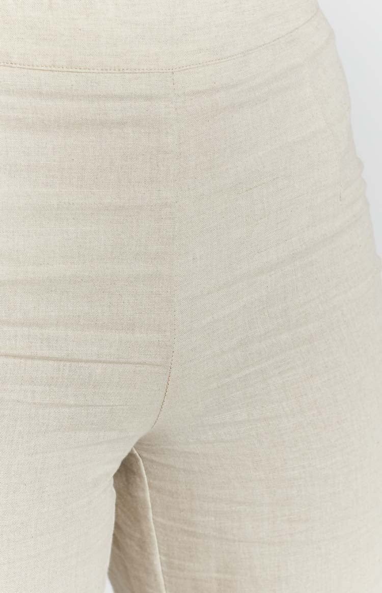 Beige high-waisted wide-leg pants with a textured fabric and midi length
