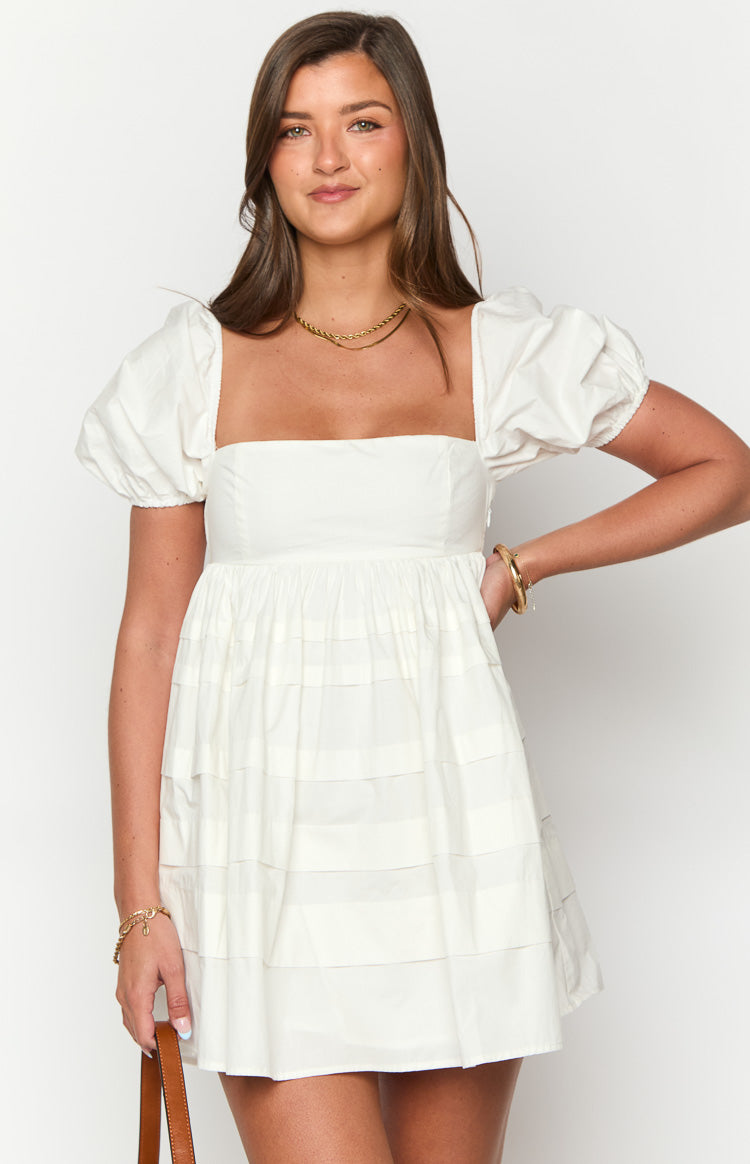 Front view of a white babydoll mini dress with a square neckline, puffy short sleeves, and a tiered skirt