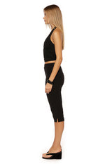 Side view of black jersey capri pants with a fitted silhouette and small side slits at the hem