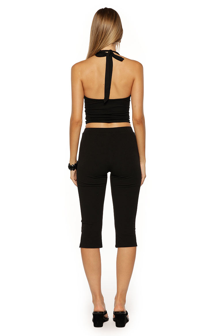 Rear view of black jersey capri pants, showing the smooth fabric, fitted silhouette, and cropped length