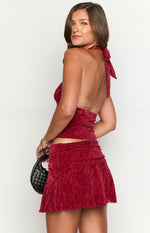 Rear view of a red patterned velvet mini skirt with a ruched waist and slight flare
