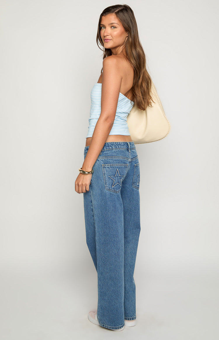 Rear-side view of mid wash denim low rise jeans with star embroidery on the back pockets and a wide leg fit