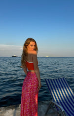 Rear view of an orange and pink floral satin maxi skirt with a flowy silhouette