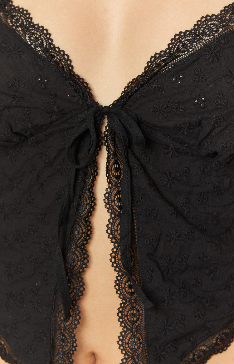 Close-up of the black tie front closure and lace trim on the embroidered top