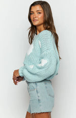 Close-up of a light blue chunky knit sweater with white cloud appliques and oversized balloon sleeves
