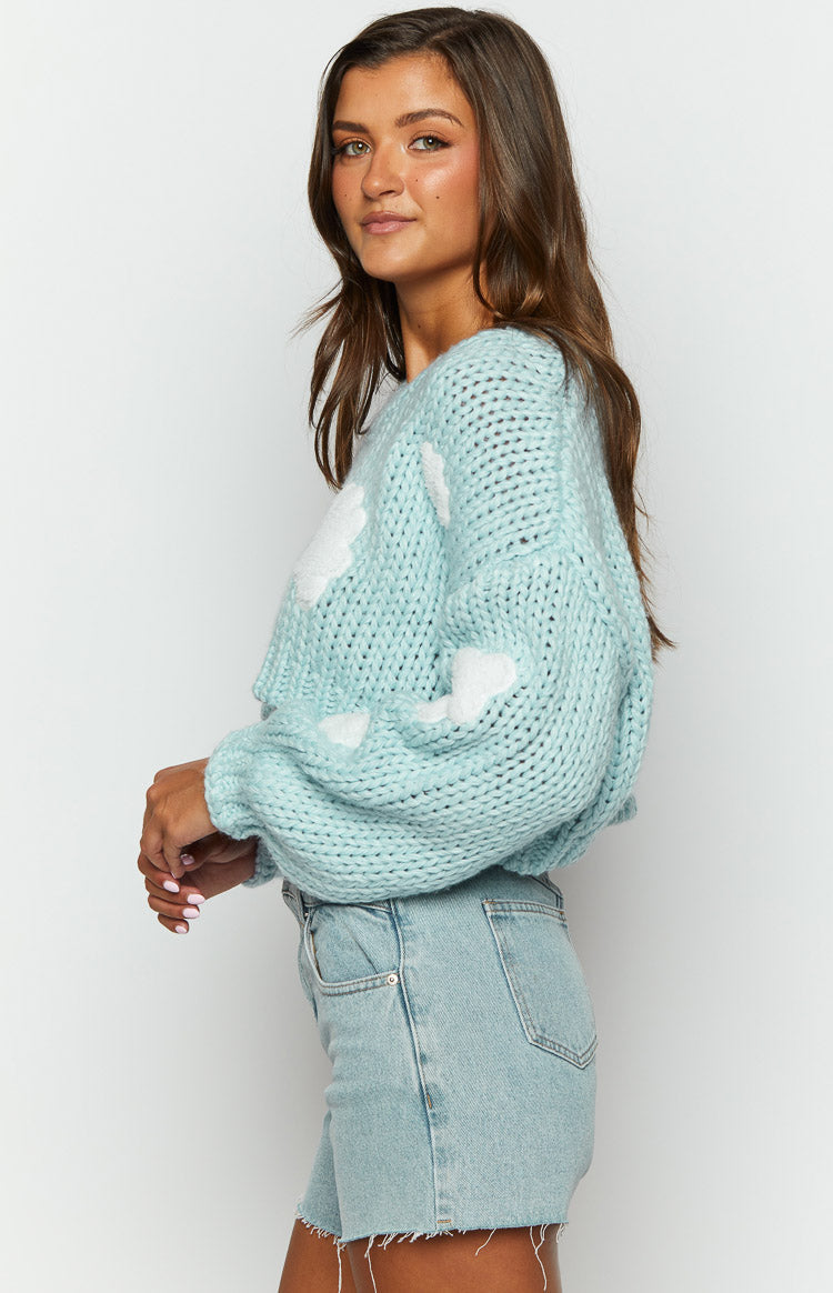 Light blue chunky knit sweater with white cloud appliques, wide crew neck, and relaxed oversized fit