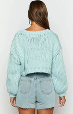 Close-up of the chunky knit texture and white cloud appliques on a cloud blue cropped sweater