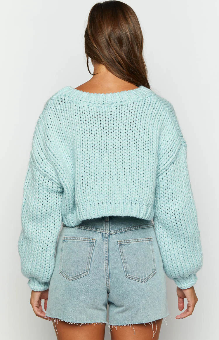 Close-up of the chunky knit texture and white cloud appliques on a cloud blue cropped sweater