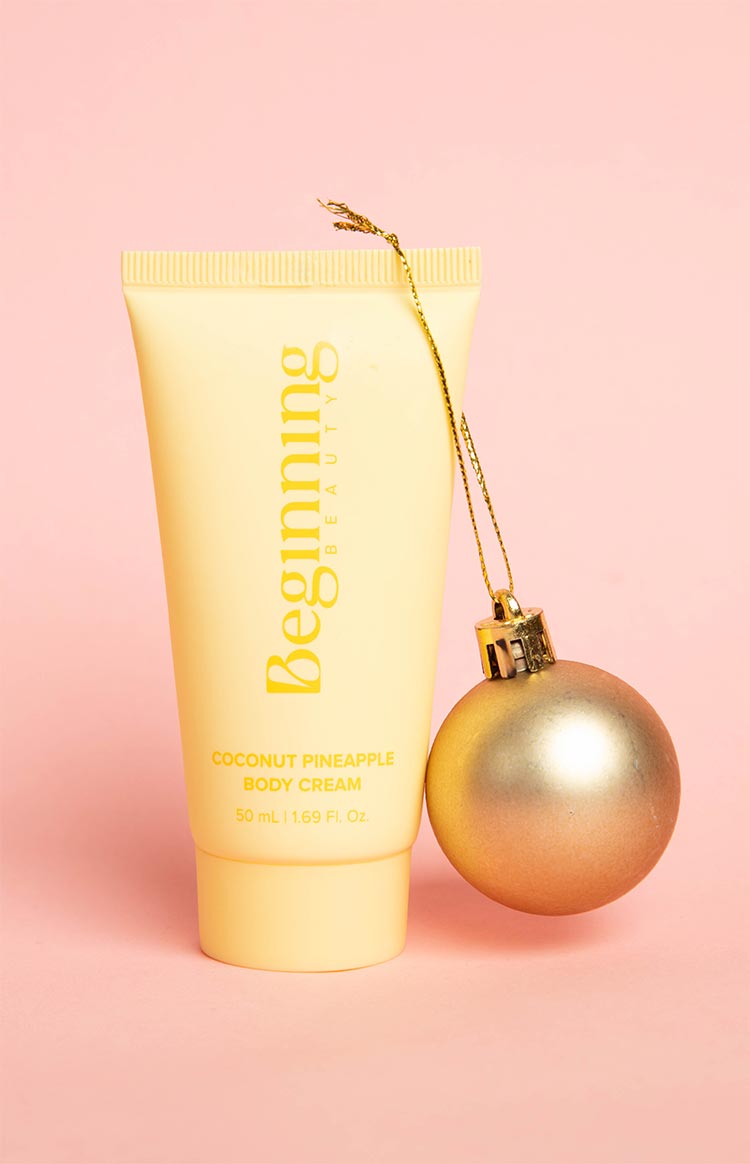 Light yellow tube of body cream with 'Coconut Pineapple Body Cream' and volume details printed on the front