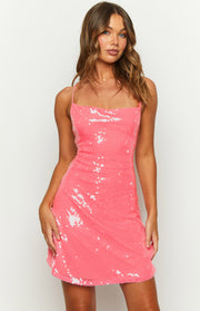 Close-up front view of a pink sequin mini dress with a cowl neckline, thin spaghetti straps, and scattered white sequins
