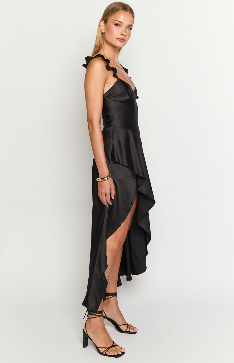 Side view of a black satin maxi dress with ruffled shoulder straps and an asymmetrical high-low hem with ruffles