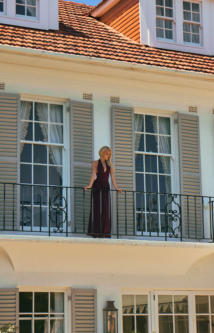 Full length view of a burgundy halter neck maxi dress with a deep V-neckline and flowy skirt