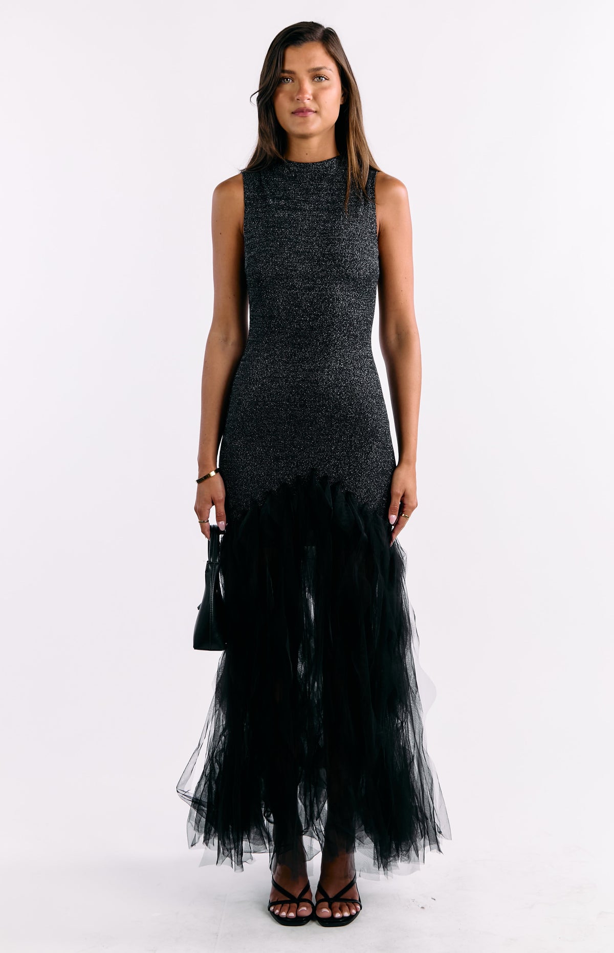 Full length front view of a black sequin sleeveless maxi dress with a high neck and voluminous ruffled tulle skirt