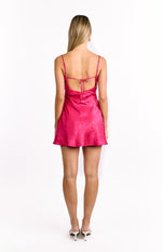 Back view of a pink satin mini dress featuring a subtle floral jacquard, low scoop back, and adjustable tie-back straps