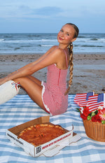 Side view of a fitted red gingham mini dress with thin spaghetti straps, a side zipper, and white lace trim