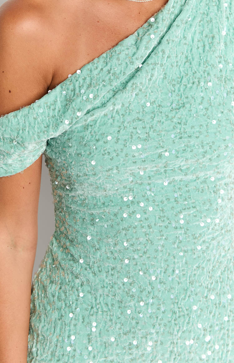Close-up of the textured teal sequin fabric with a velvet base and the draped one-shoulder neckline of the dress