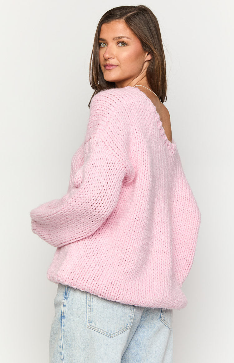 Side view of a light pink chunky knit sweater with a wide off-shoulder neckline and long sleeves