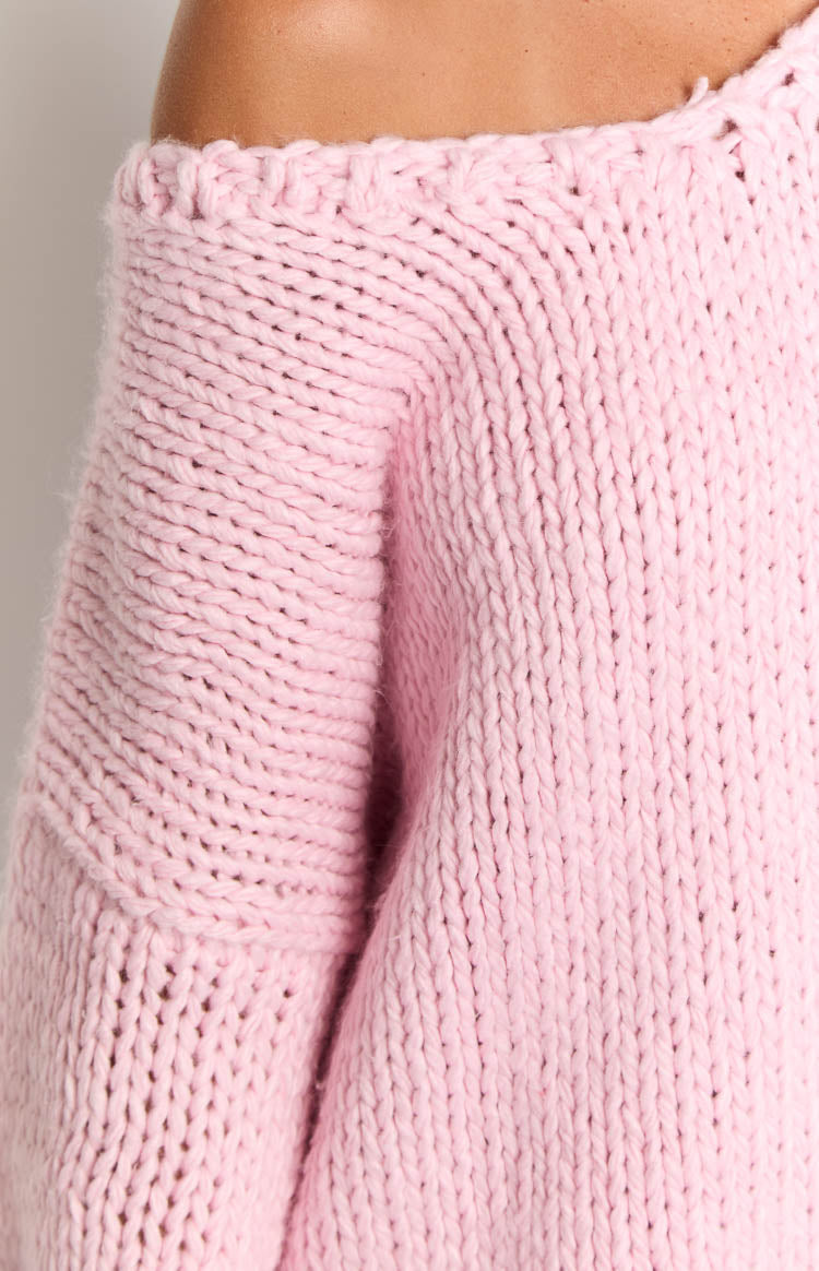 Close-up of the light pink chunky knit sweater showing the off-shoulder neckline and thick knit texture