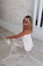 Front-side view of white sheer lace pants featuring an intricate all-over sequin pattern