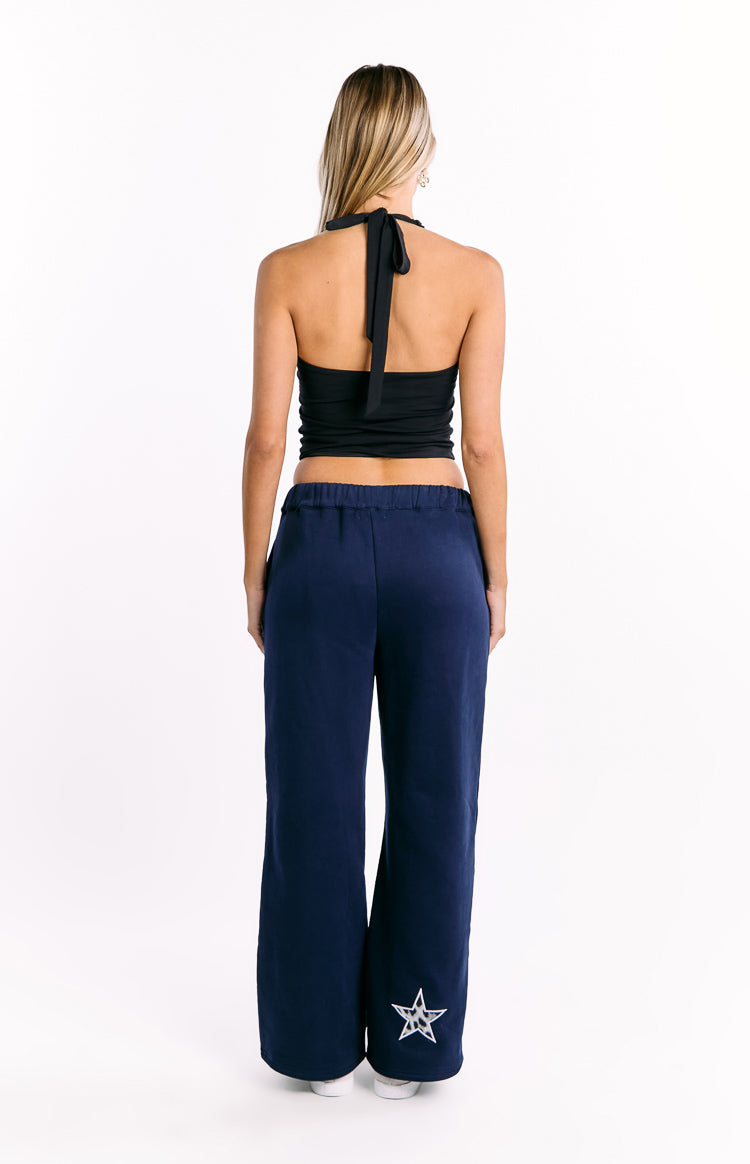 Rear view of navy wide-leg track pants with an elasticated waist and white leopard print star on the left leg