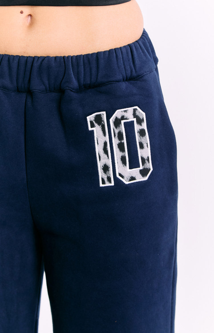 Close-up of the elasticated waistband and leopard print '10' graphic on navy track pants