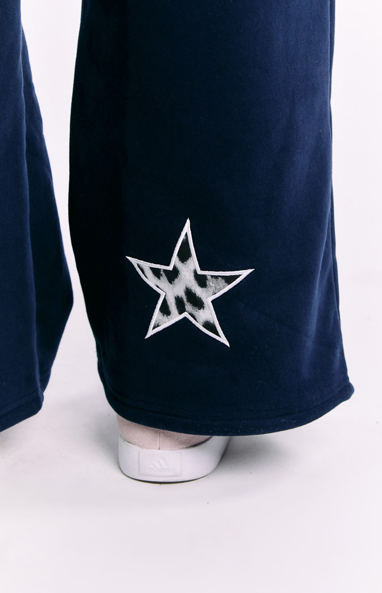 Close-up of the white-outlined star with grey leopard print on the navy track pants leg