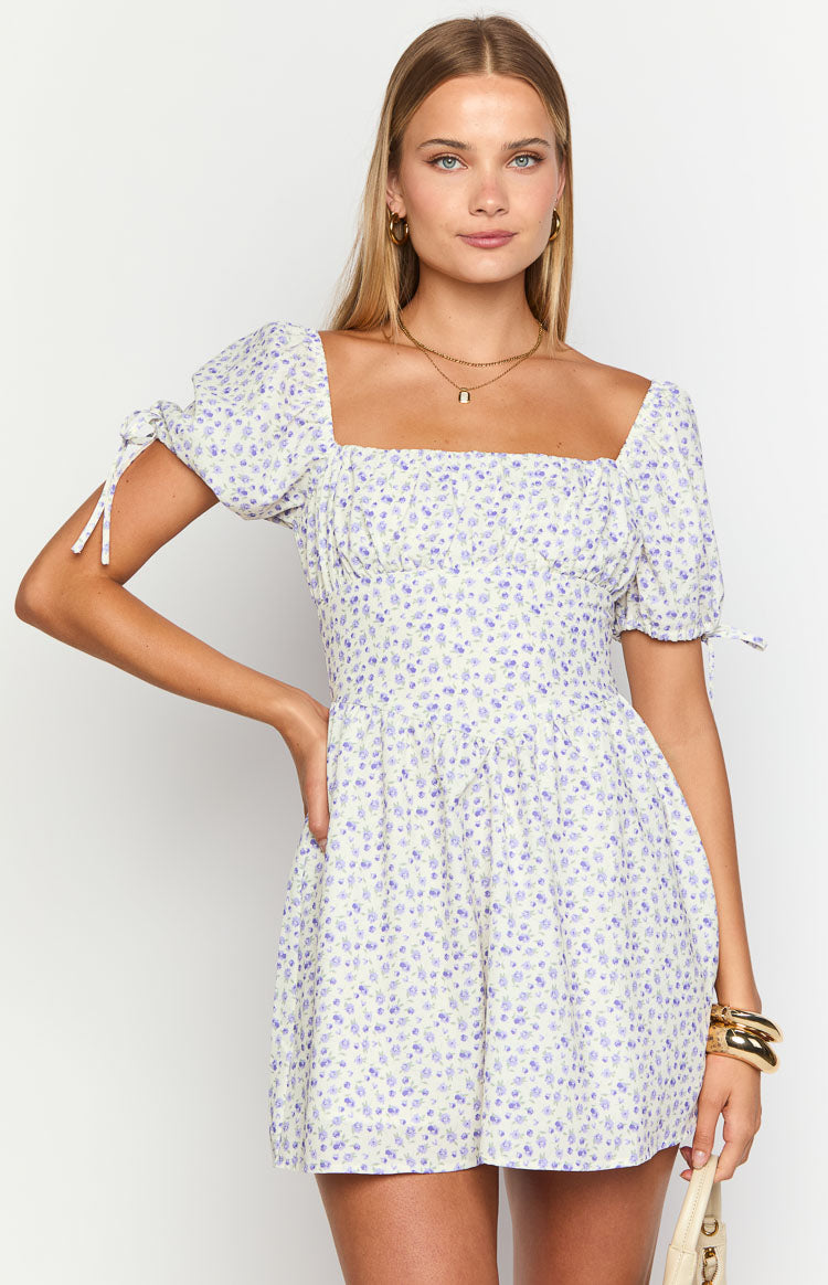 Front view of a light purple floral mini dress featuring a square neckline, ruched bust, and puff sleeves with tie details