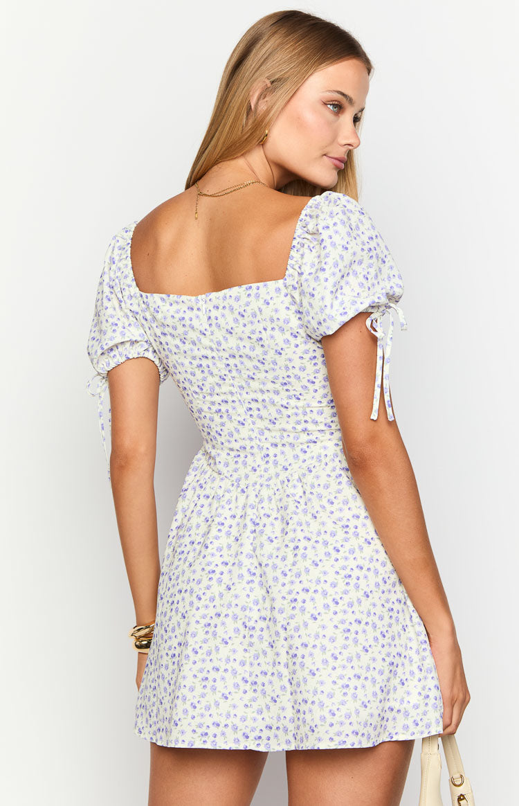 Rear-side view of a purple floral mini dress with a square back neckline, shirred bodice, and puff sleeves with tie details