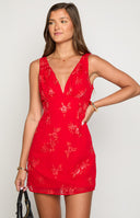 brunette girl wearing a red mini party dress with floral sequin embellishments 