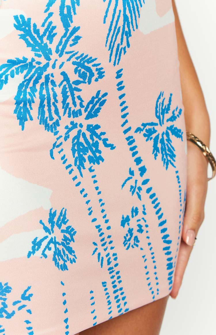 Close-up of the pink mini skirt fabric with blue palm tree print and white cloud details