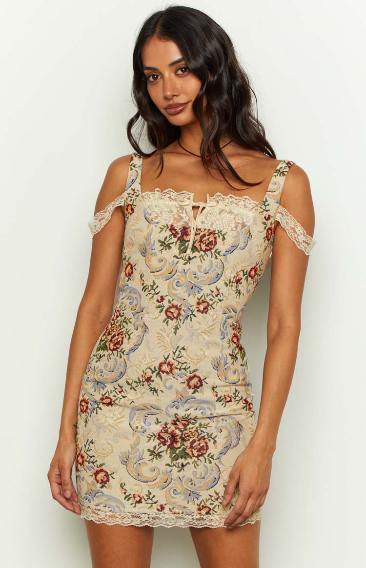 Close-up of the beige tapestry mini dress showing the square neckline with lace trim, tie detail, and off-shoulder lace straps