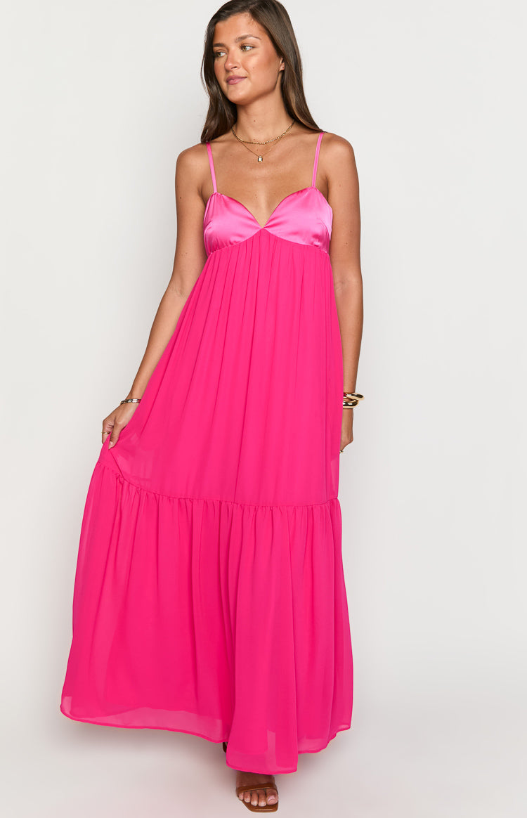 Full length view of a hot pink maxi dress with a satin sweetheart bust, spaghetti straps, and a tiered ruffle hem