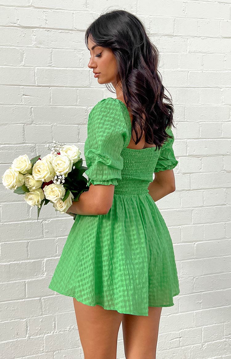 Close-up of the green playsuit showing the textured checked fabric and short puffed sleeve with elasticated cuff