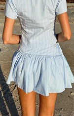 Rear view of a light blue pinstripe mini skirt with a gathered hem and side tie waist detail