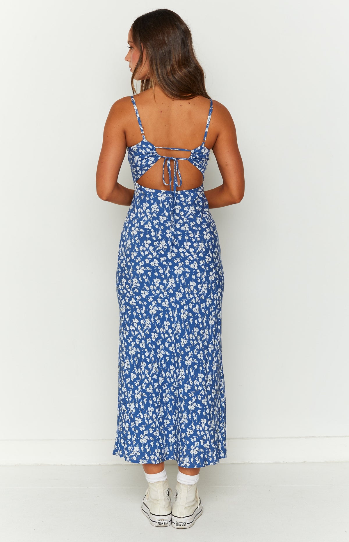 Rear view of a blue floral midi dress with an open back and tie detail