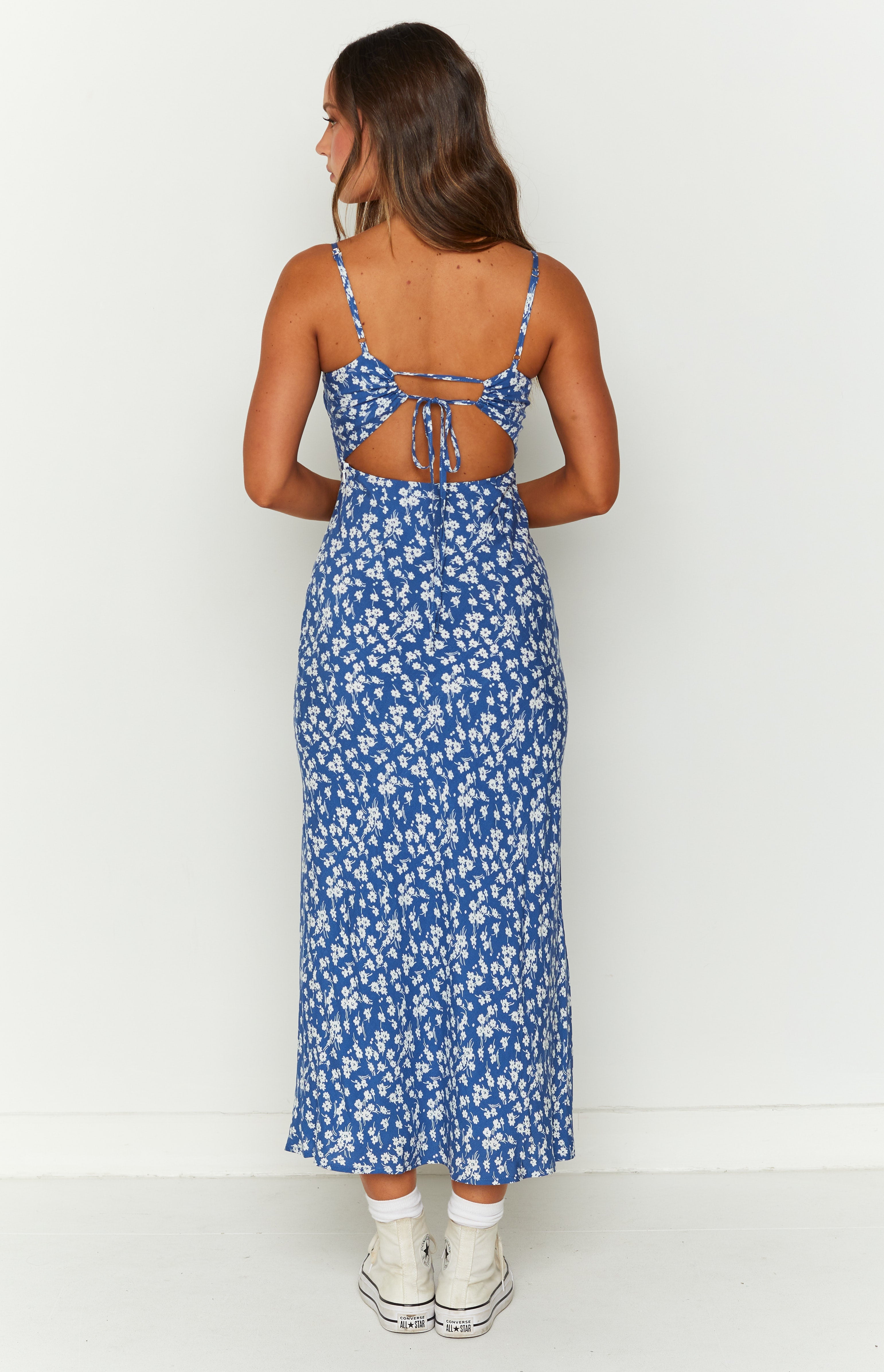 Rear view of a blue floral midi dress with an open back and tie detail