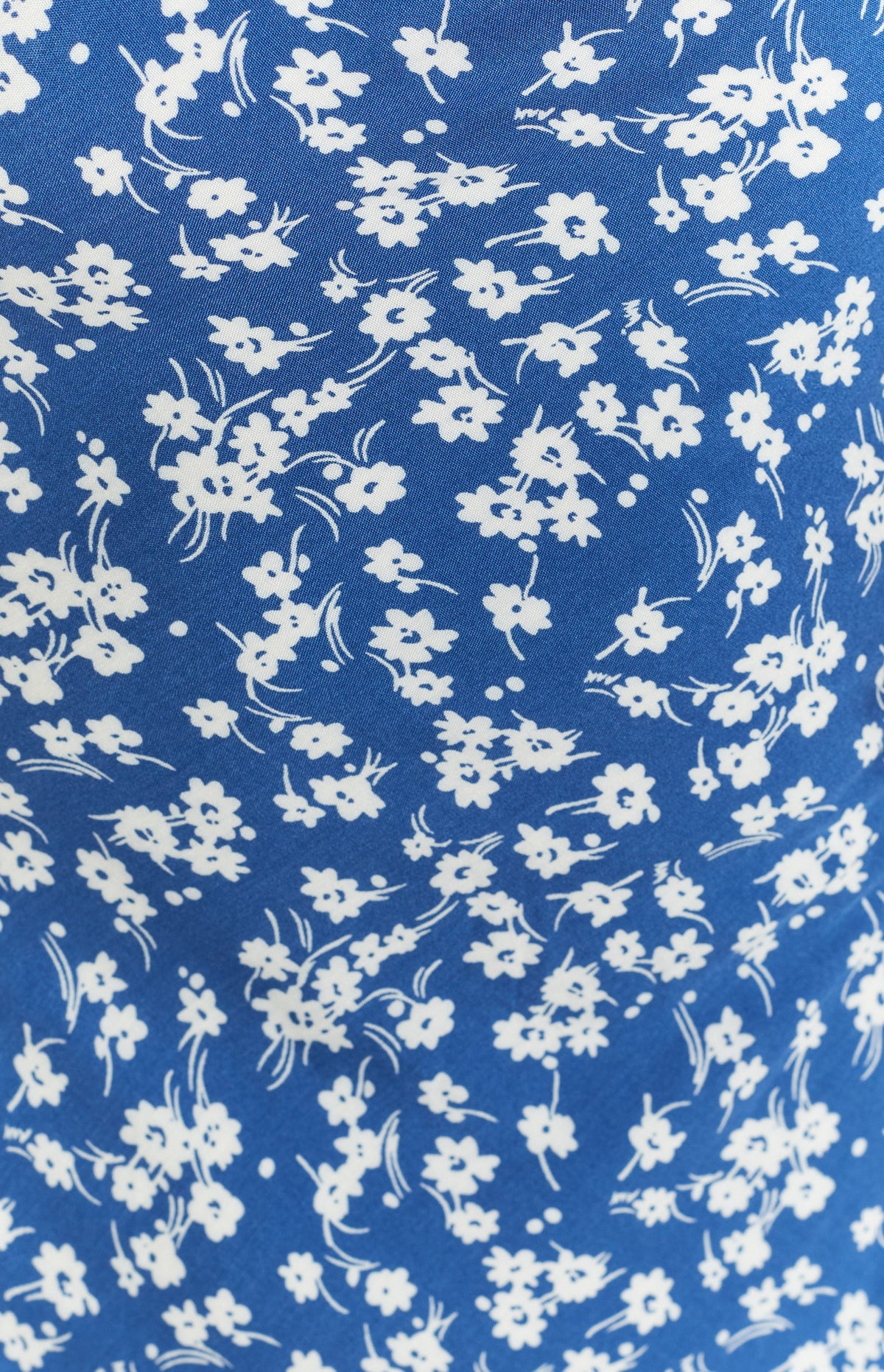 Close-up of the blue fabric with delicate white floral print on the midi dress
